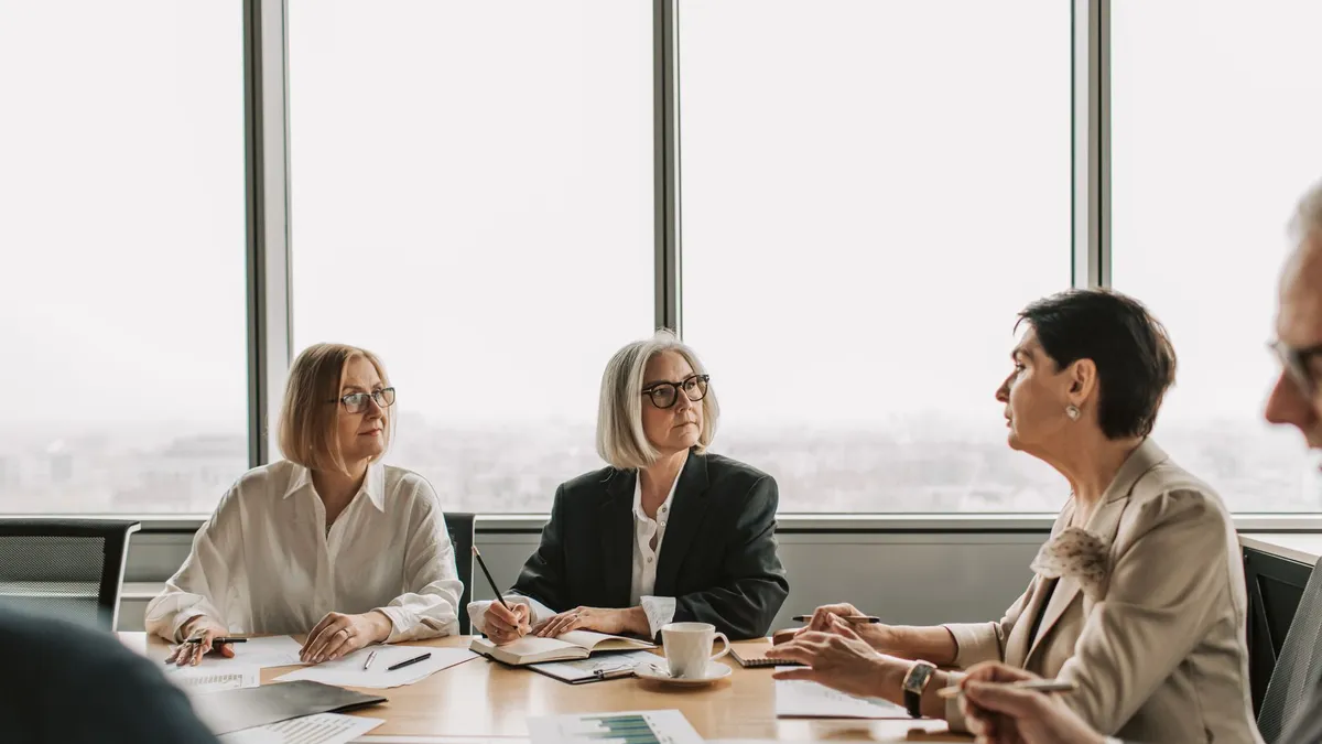 A group of senior executives engaged in a serious business meeting in a modern office setting.