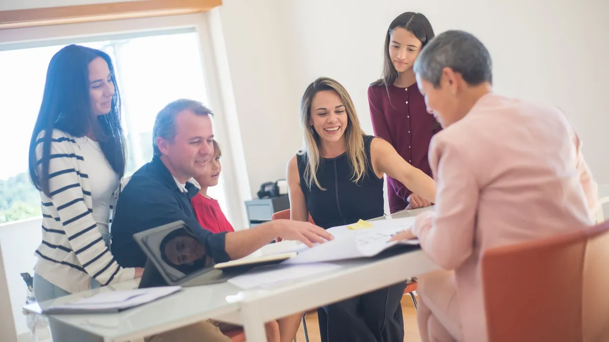 A happy family gathering around a desk during a home meeting, discussing documents.