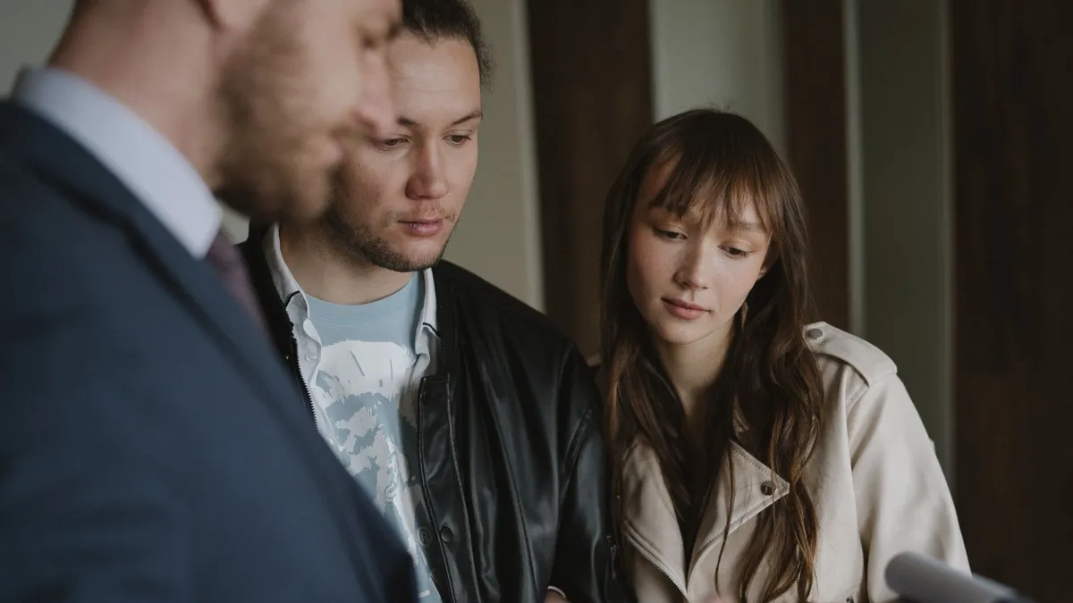 A couple discusses home buying details with a realtor inside a modern apartment.