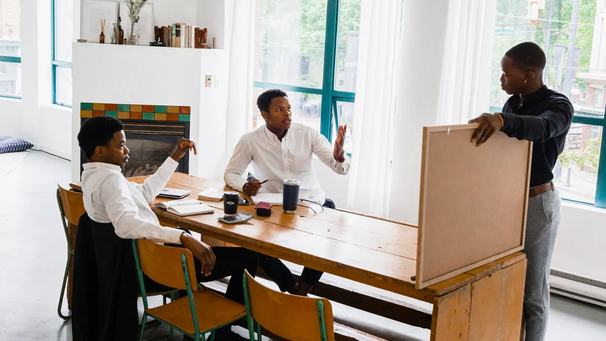 Three men discussing a project at a table in a bright office setting.