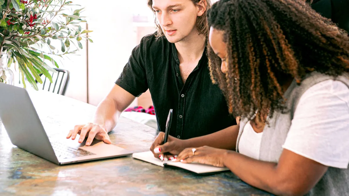 Young professionals collaborating on a project in a modern office with laptop and notes.