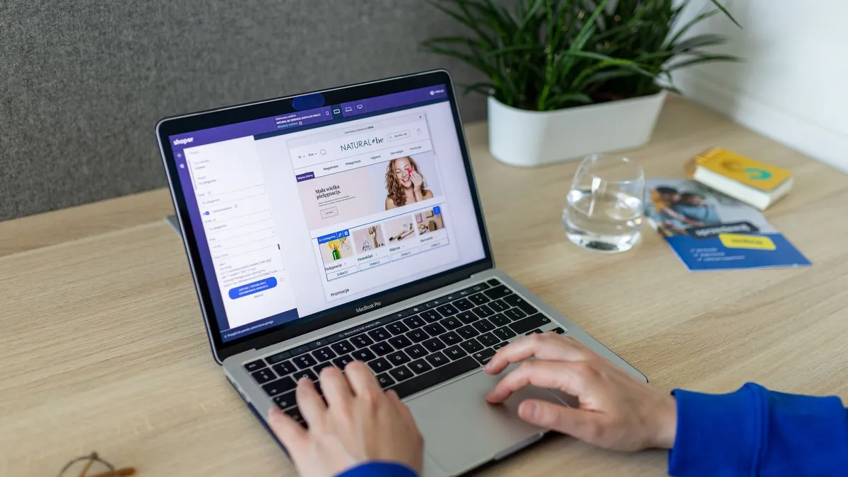 A person navigating an online store on a laptop, at a modern indoor office desk.