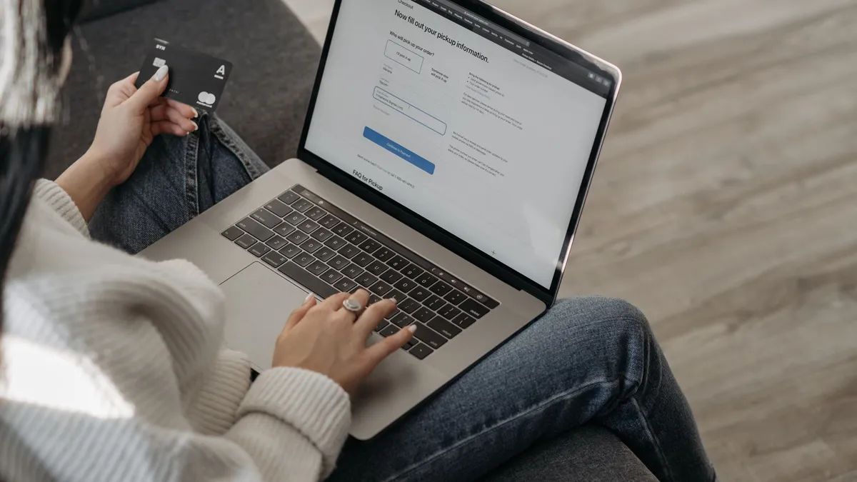 Close-up of a woman using a laptop for online shopping and holding a credit card in hand.