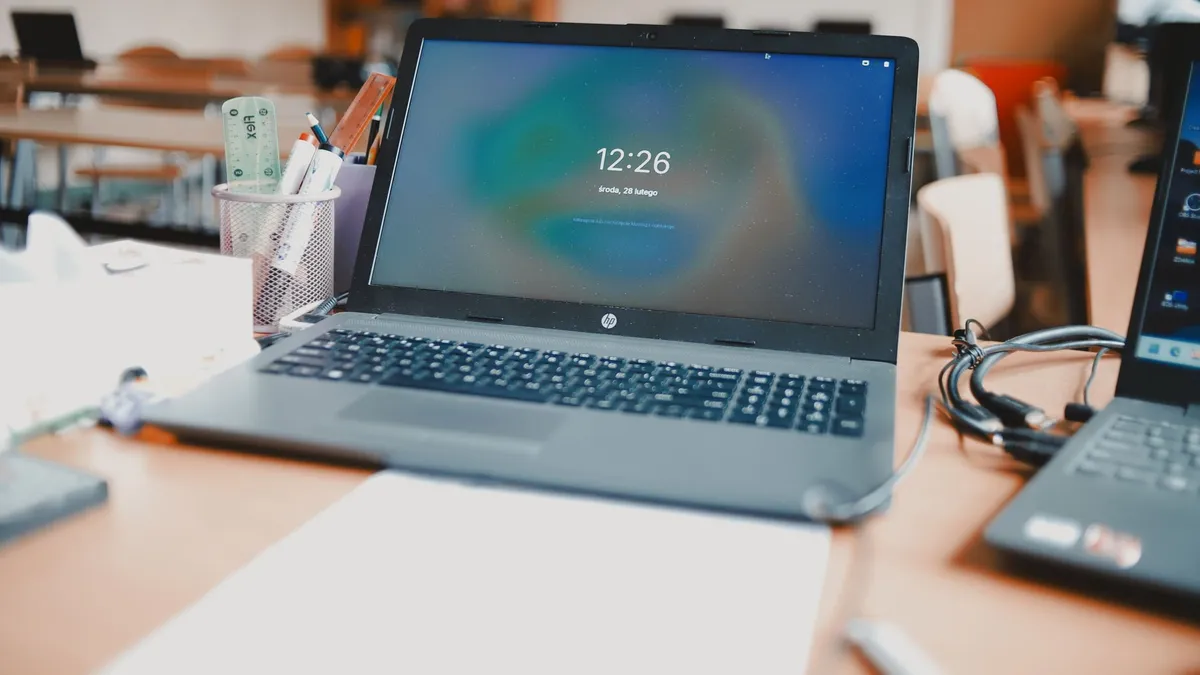 A classroom setting featuring laptops and desks, capturing a modern educational environment.
