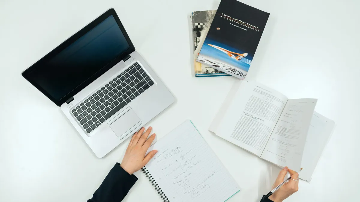 Top view of a work desk with laptop, books, and notes showcasing productivity.
