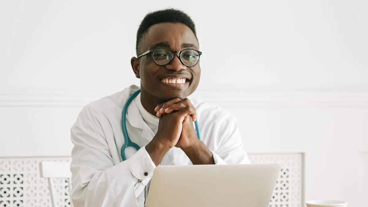 Happy doctor wearing eyeglasses and stethoscope smiling confidently at his workplace.