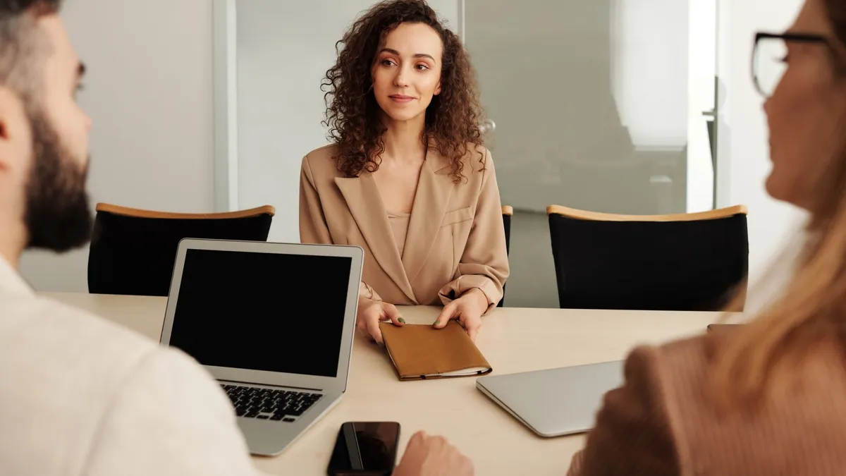 A woman in a business suit participates in a job interview, showcasing professionalism and modern office environment.