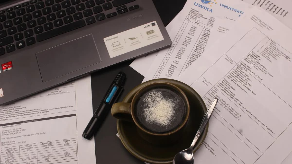A close-up view of a desk with a coffee cup, documents, and a laptop for a productive work session.