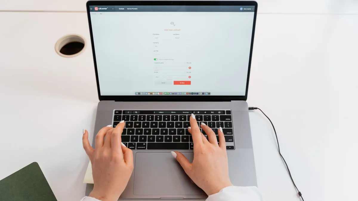 Close-up of hands typing on a laptop in a modern office environment.