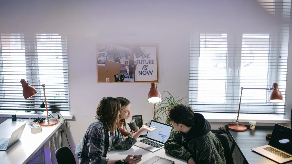 A group of people discussing ideas around laptops in a bright, modern office space.