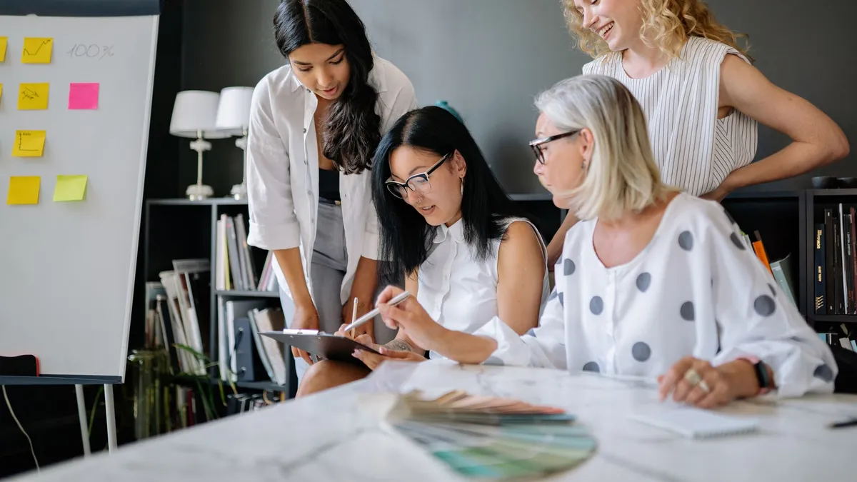 A diverse group of women engaged in a collaborative business meeting in a modern office setting.