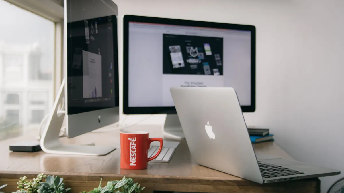 A bright modern office setup with computers and a mug on a desk.