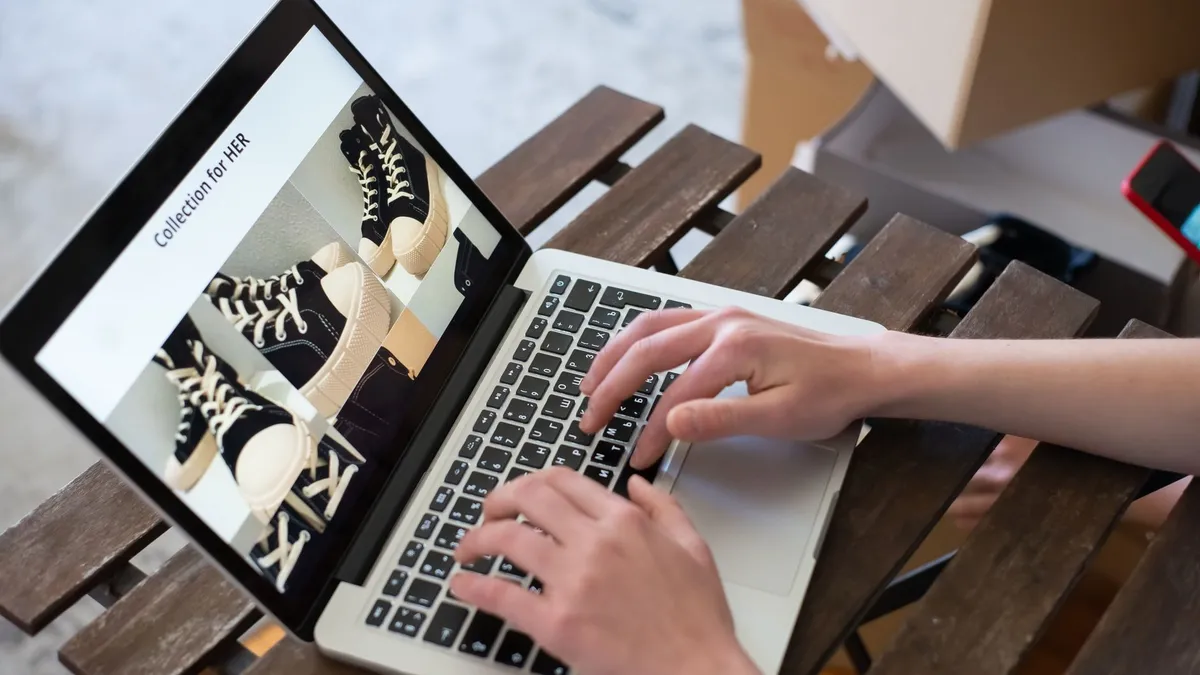 Hands of a person browsing a Collection for HER on an online shoe store using a laptop.