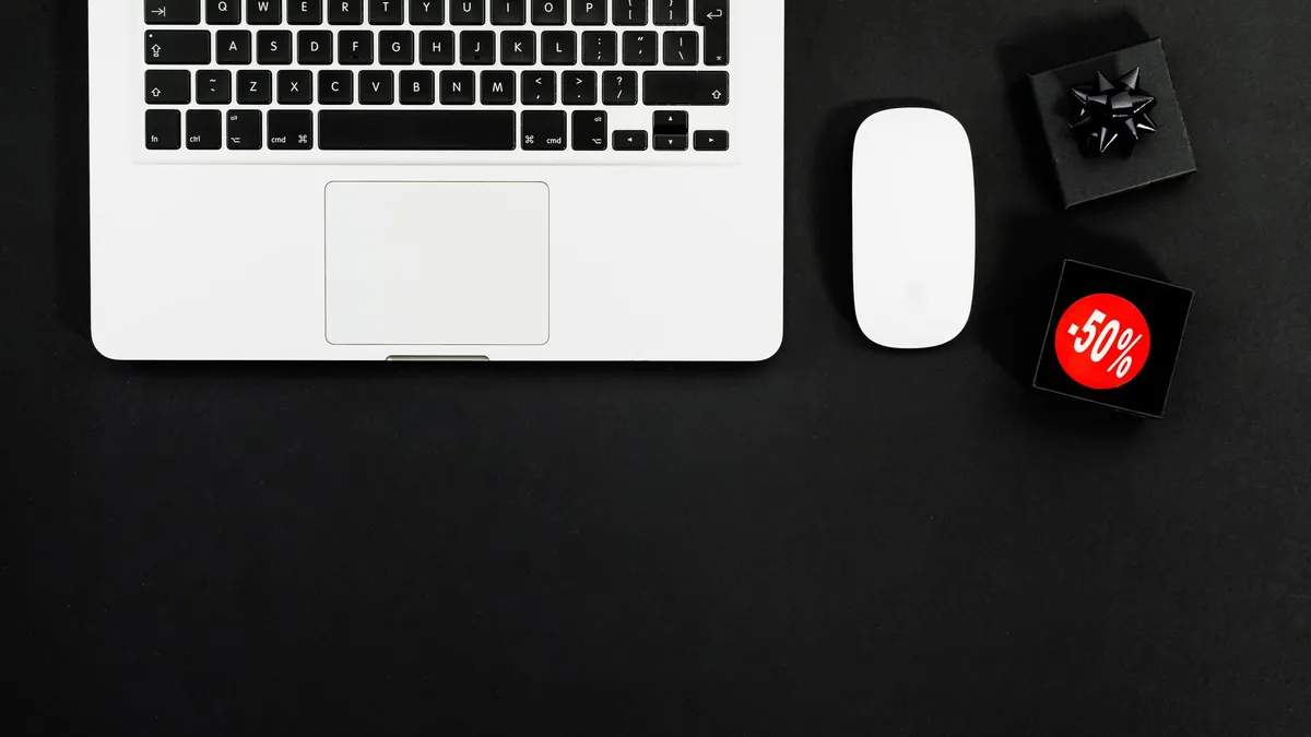 Minimalist flat lay featuring a laptop and shopping items with 50% sale tags.