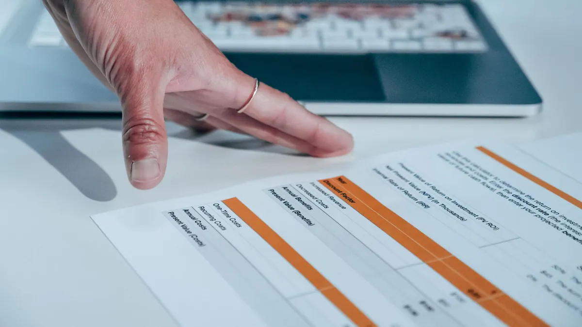Close-up of a hand reviewing a financial report on a laptop, indicating focus on business analysis.