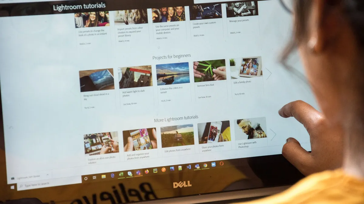 A woman exploring Adobe Lightroom tutorials online for learning and photo editing.