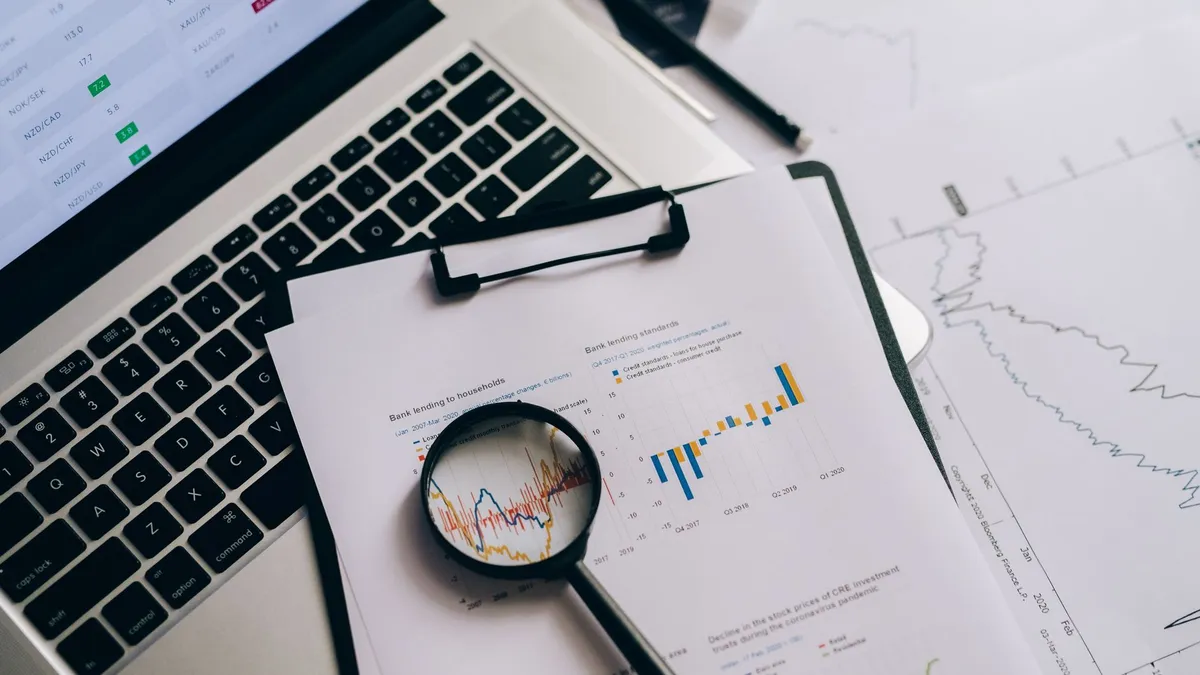 Overhead view of financial charts, laptop, and magnifying glass, ideal for business analysis themes.