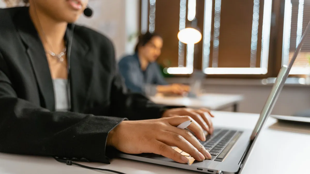 Call center agents working on laptops in a modern office setup.