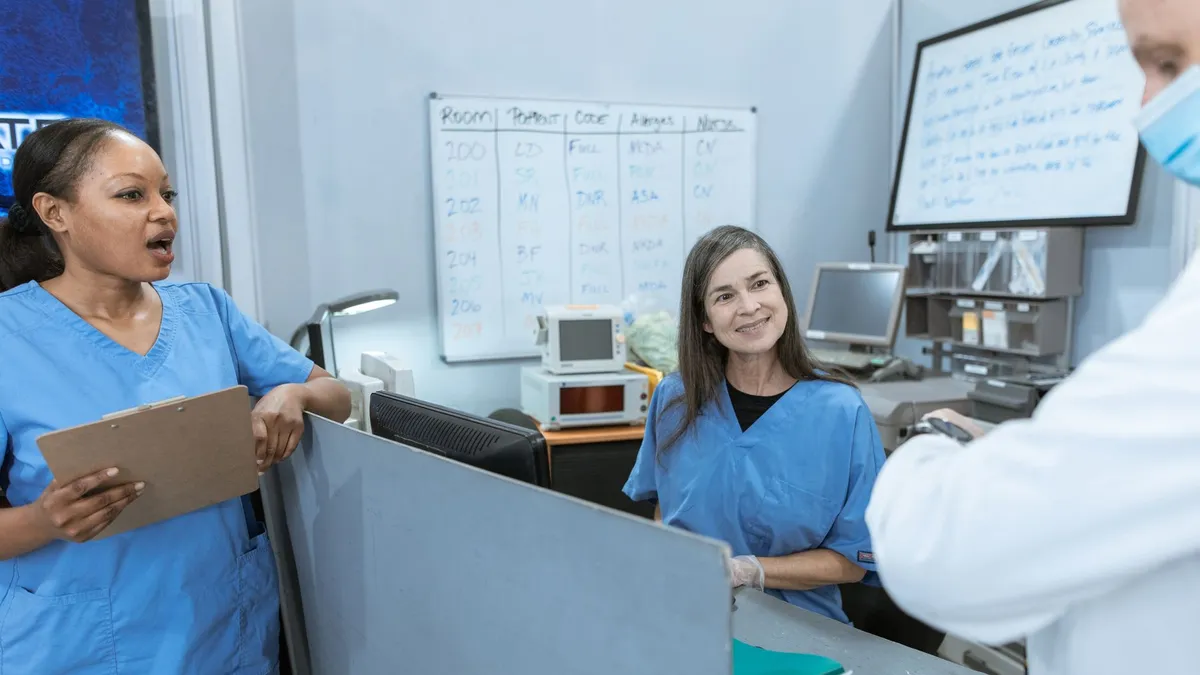 Group of nurses and a doctor collaborating at a hospital reception area with medical equipment in view.