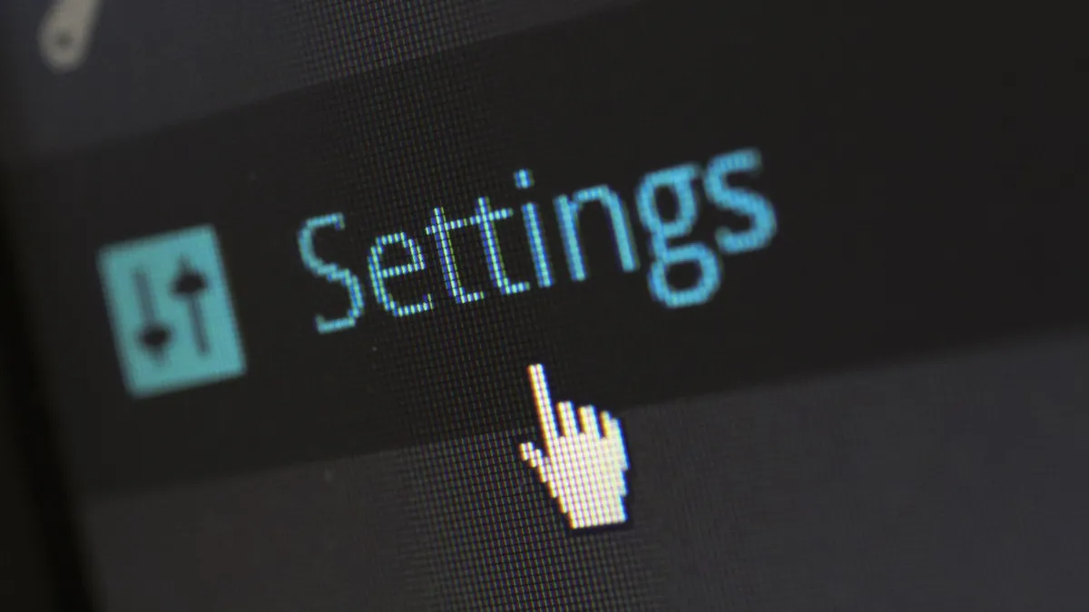 A close-up photo of a computer screen showing the settings button with a cursor hovering over it.