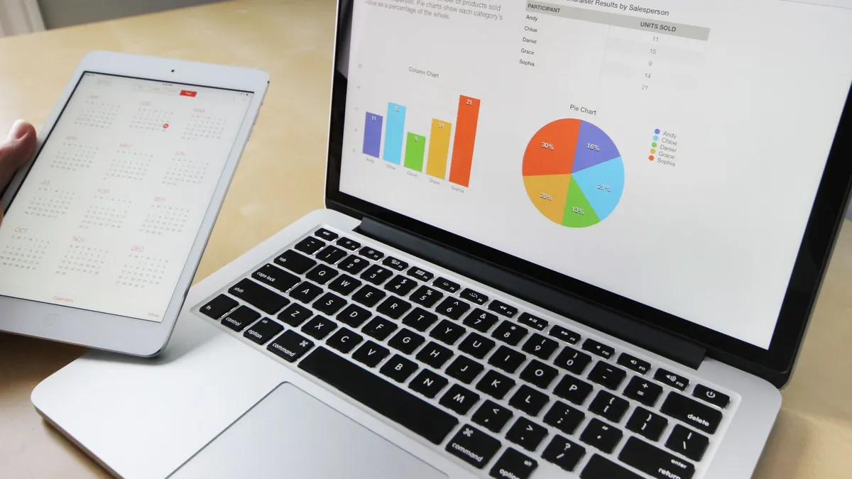 Laptop displaying charts and graphs with tablet calendar for data analysis and planning.