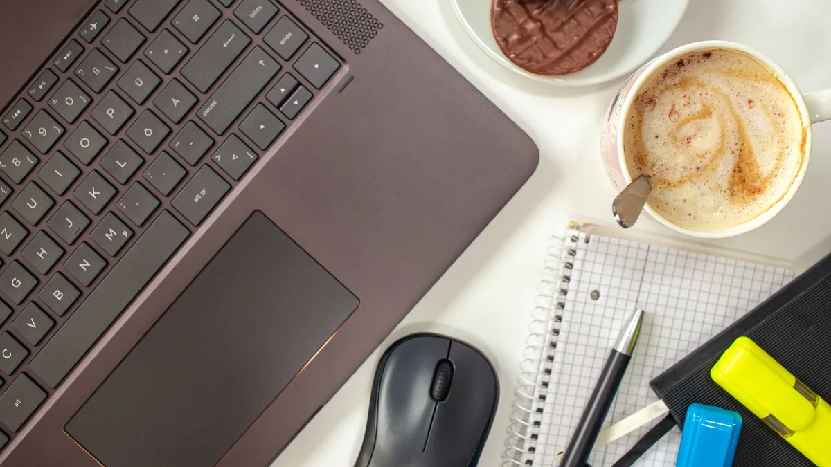 Top view of a cozy workspace featuring a laptop, coffee, and cookies.