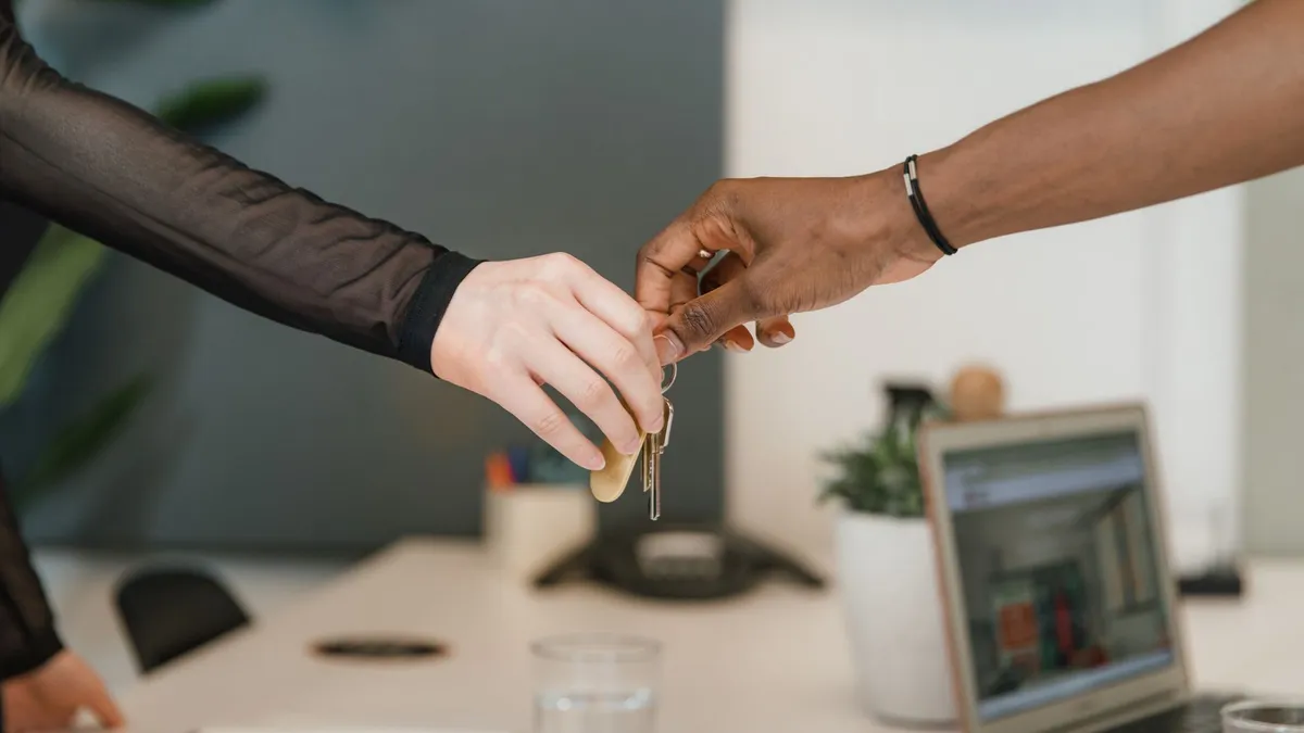Professional office setting showing a key exchange symbolizing a business deal or real estate transaction.