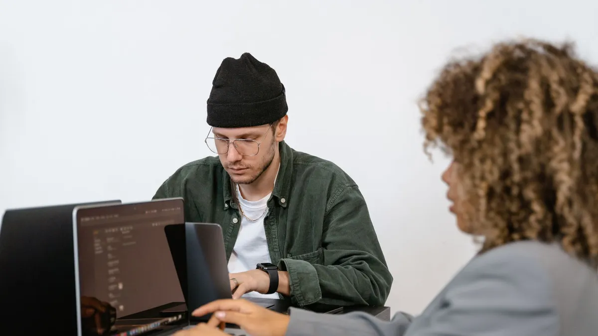 Two professionals working intently on laptops in a modern collaborative office environment.