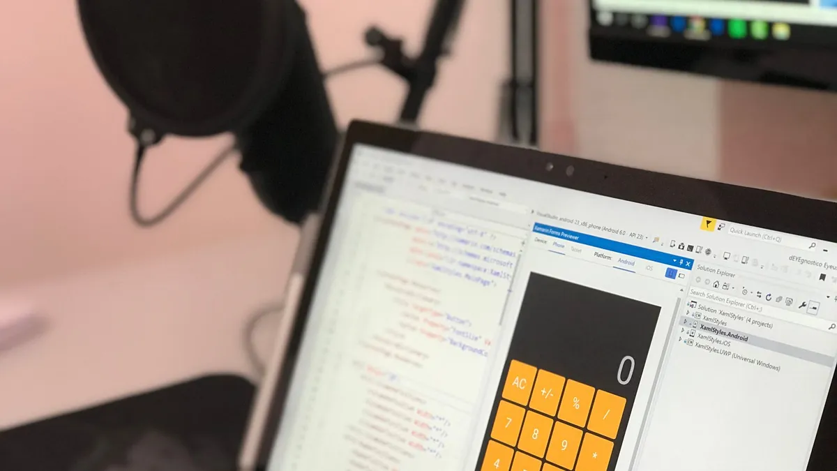 Close-up of a laptop displaying code and a calculator app in a modern workspace.