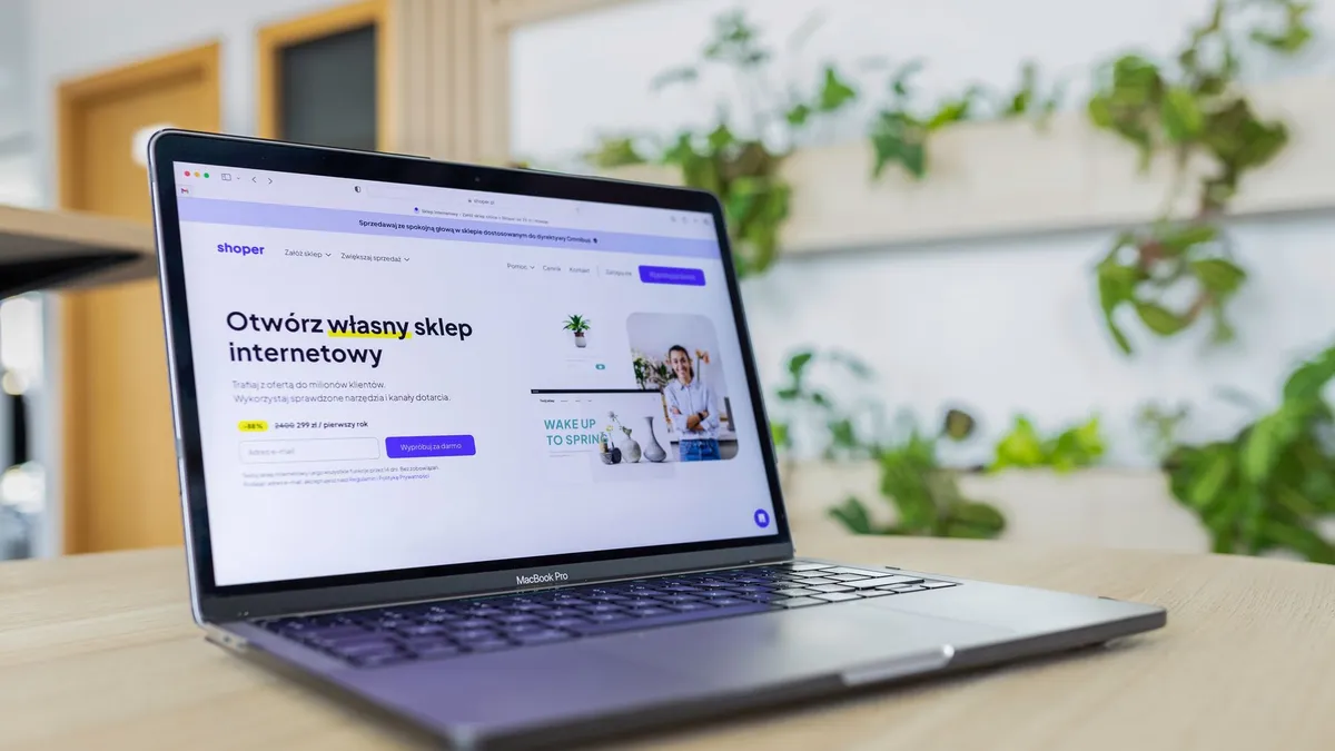 Close-up of a laptop with an open e-commerce website, surrounded by modern office decor.
