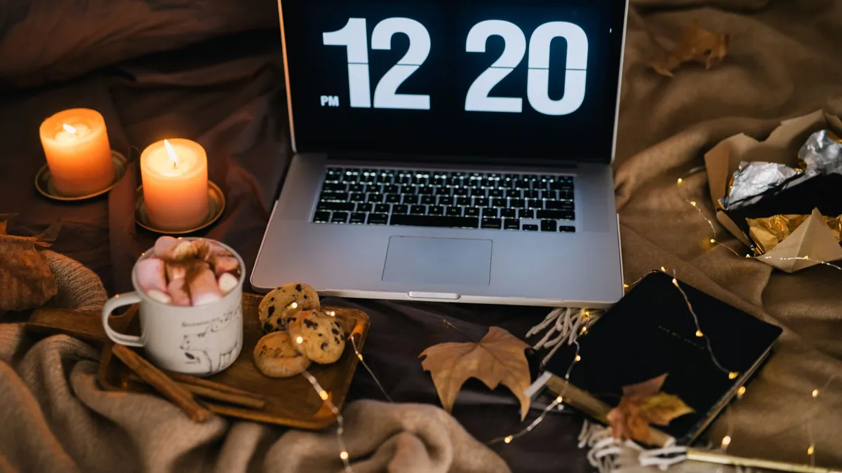 A cozy workspace with a laptop, candles, and a cup of hot chocolate, perfect for autumn evenings.