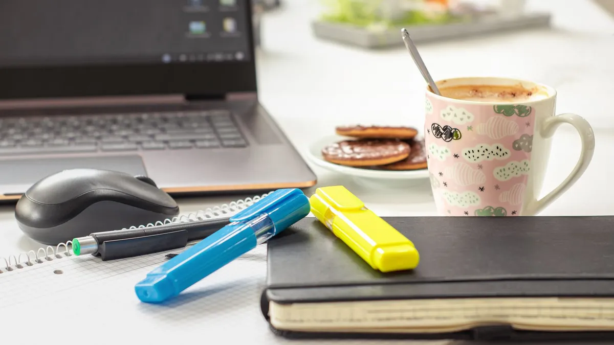 A bright and inviting workspace featuring a laptop, stationery, and a mug of coffee, perfect for productivity.