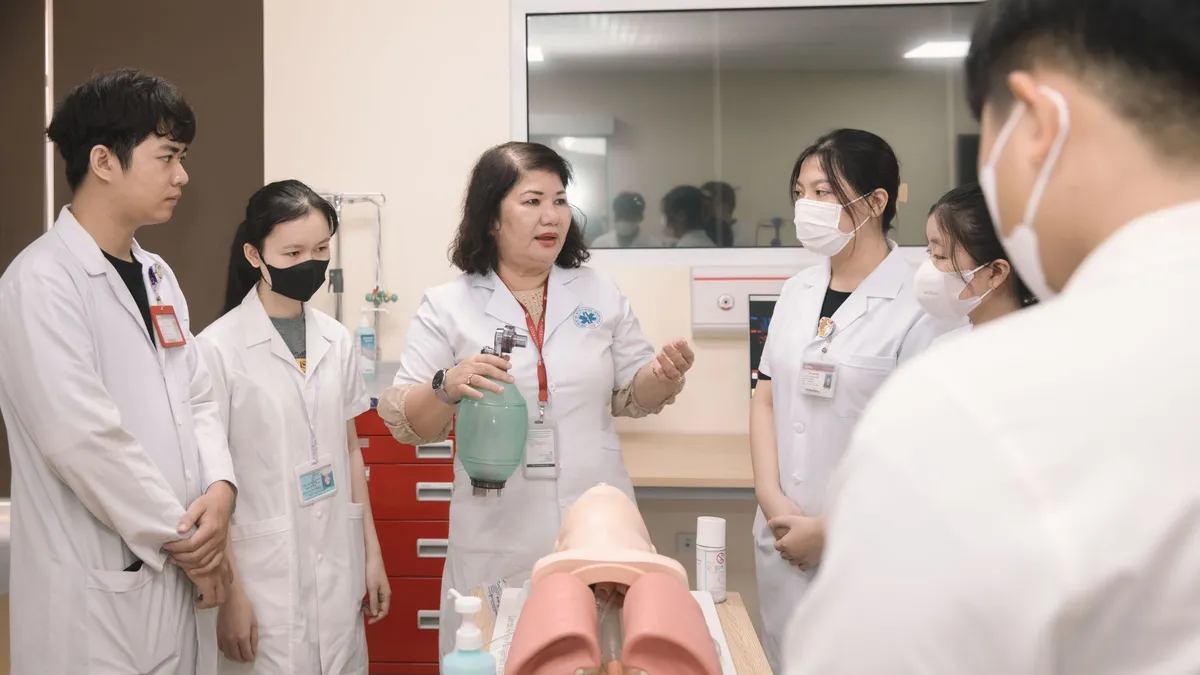Group of medical students practicing skills with a training mannequin in a classroom setting.