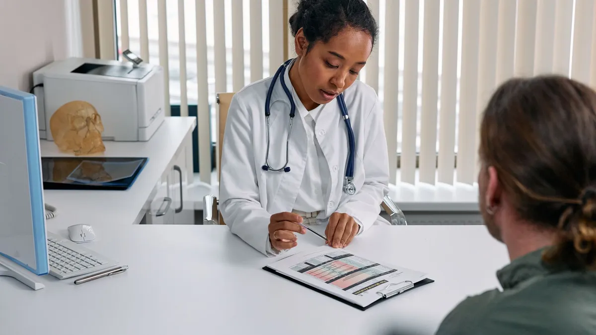 A doctor consulting with a patient in an office, discussing a medical chart.