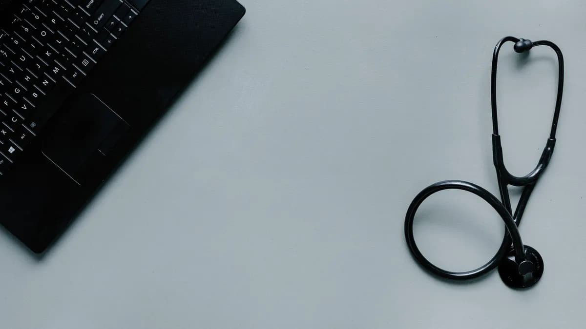 Minimalist image depicting a laptop and stethoscope representing telemedicine and digital health.