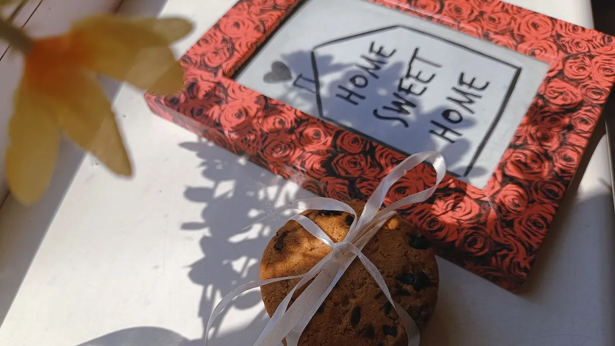 Cookies tied with ribbon and home frame on a sunlit table, evoking cozy vibes.