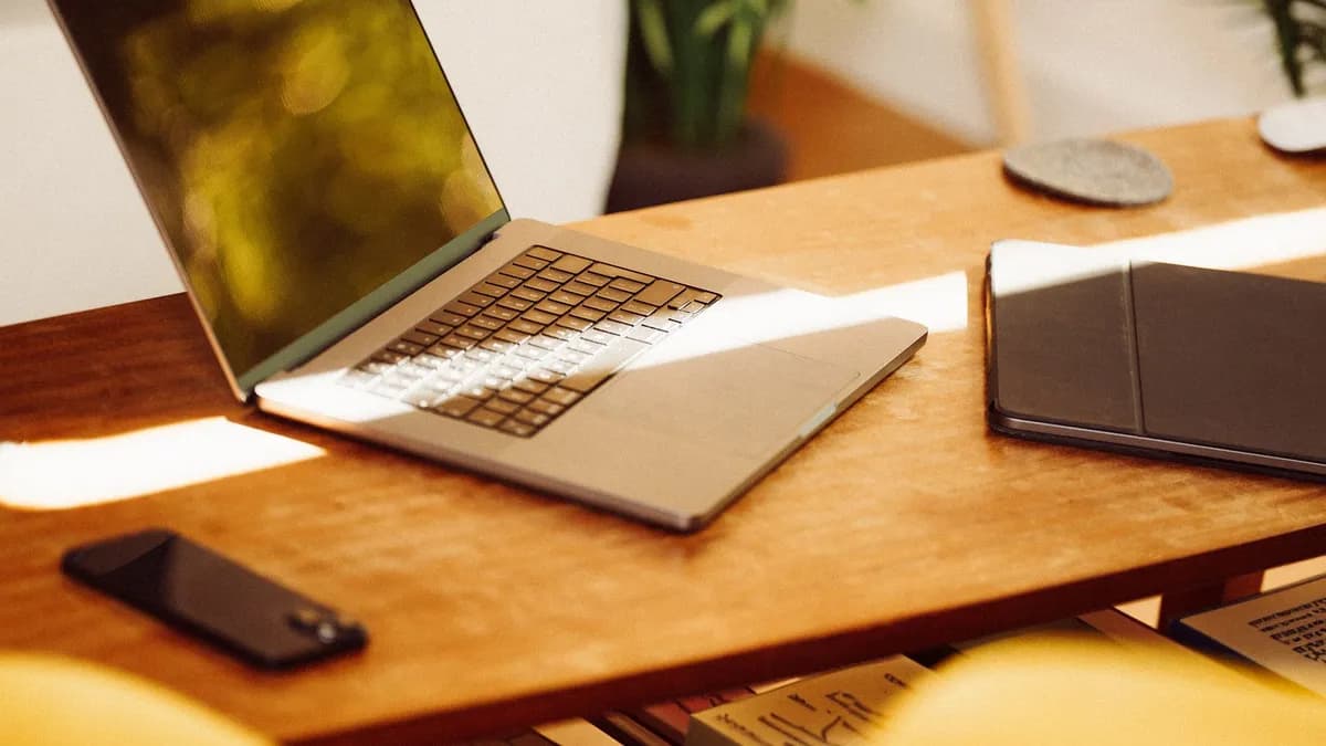 A cozy home office setup with a laptop, smartphone, and tablet on a wooden desk indoors.