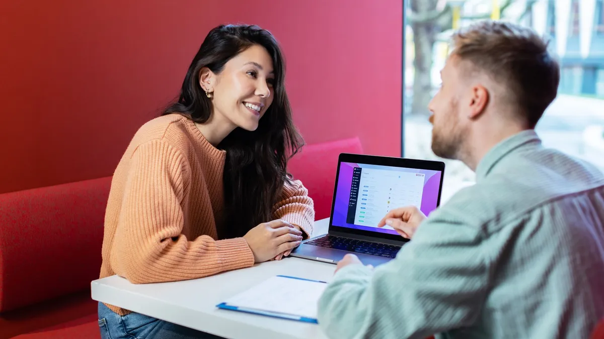 Two colleagues discussing business ideas over a laptop in a New York City cafe.
