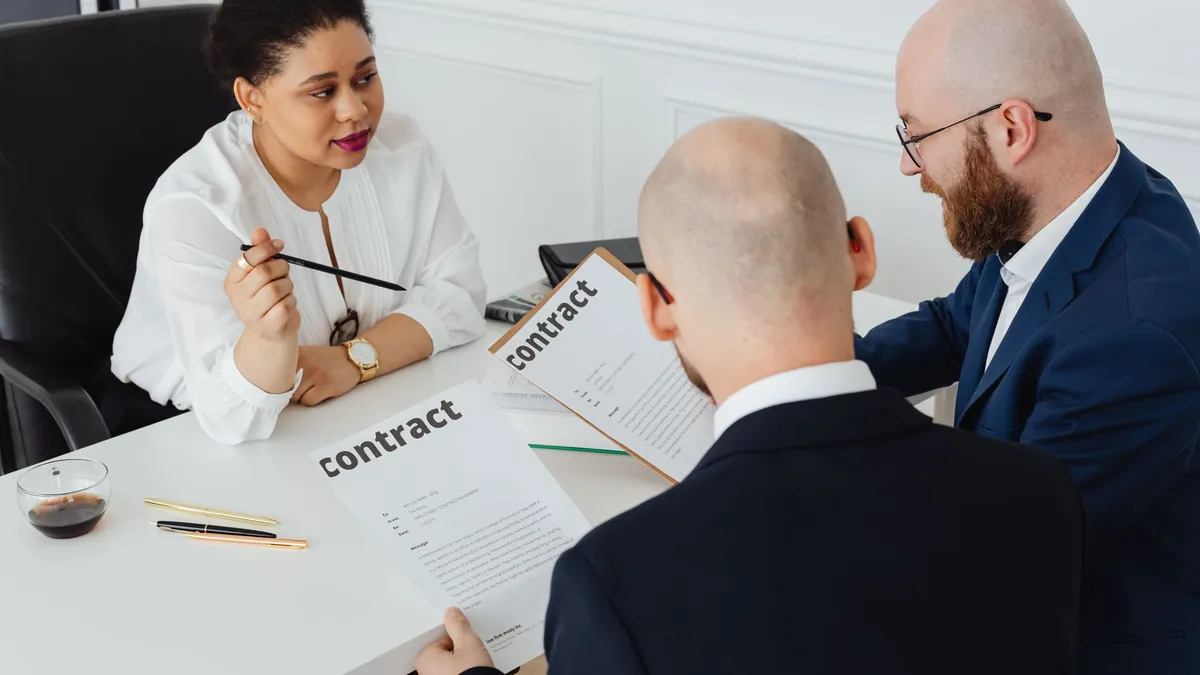 Three business professionals in discussion over a contract in a modern office setting.