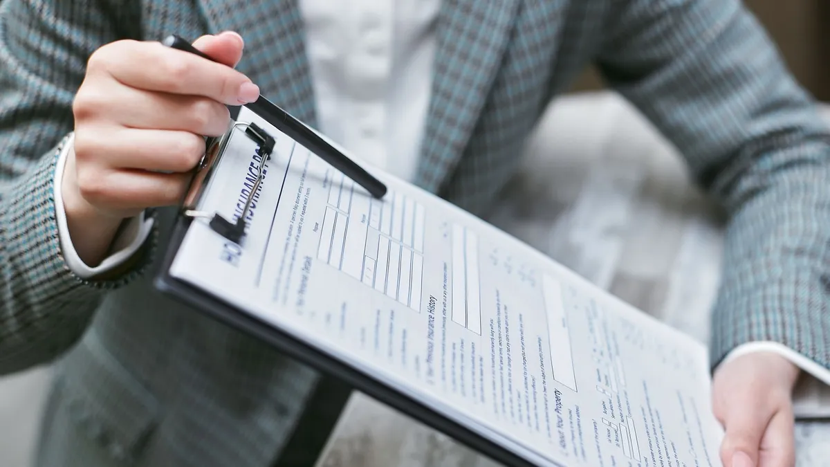 Close-up of a businessperson holding a clipboard with an insurance document, emphasizing details.