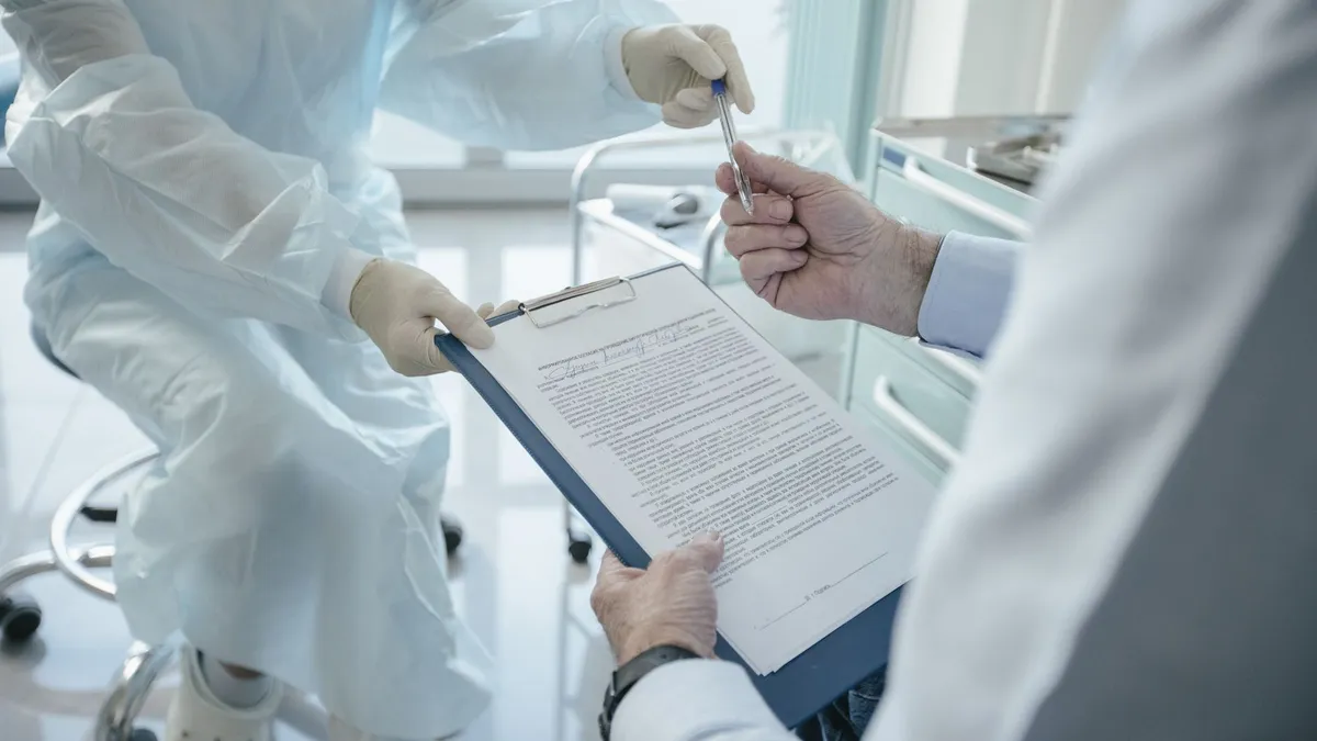 A doctor hands a clipboard to a patient for signature, highlighting medical professionalism.
