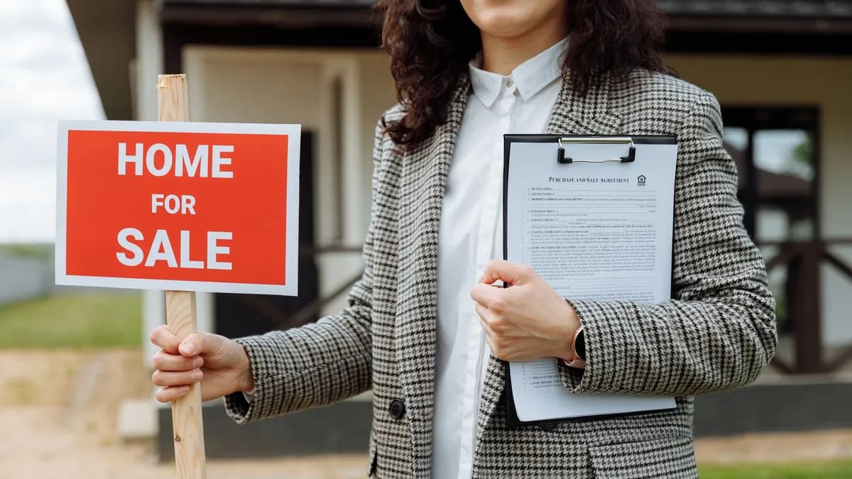 A real estate agent holding a home for sale sign and clipboard outside a property.