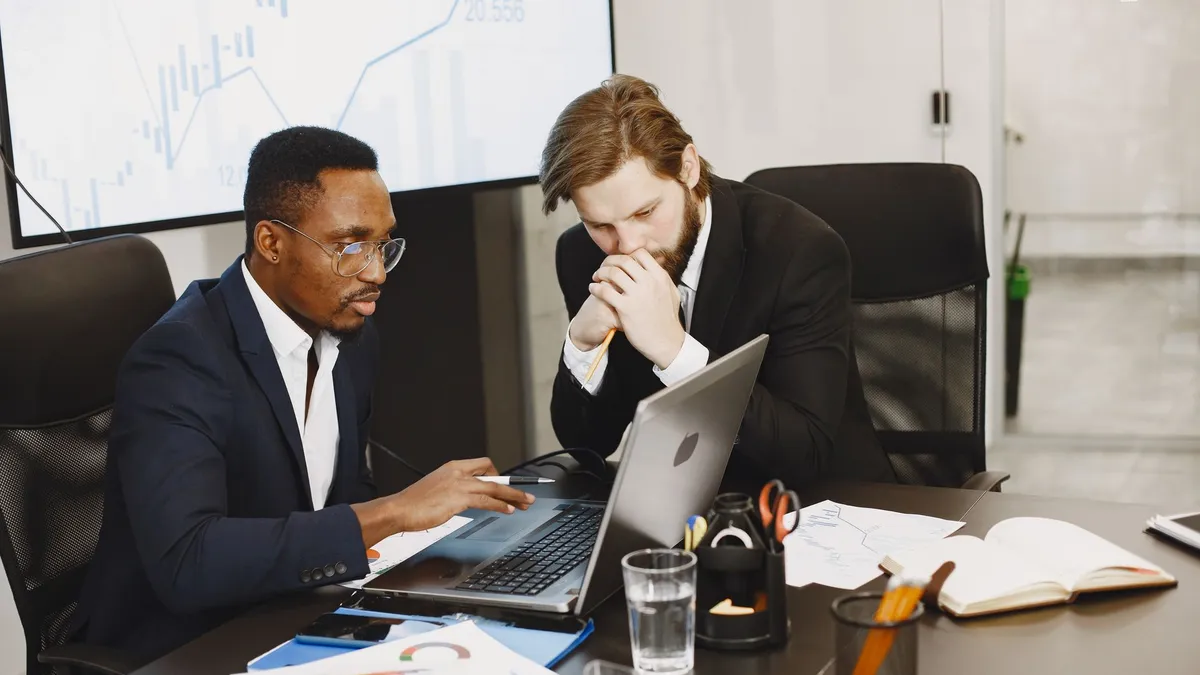 Two businessmen engaged in a strategy meeting with laptops and charts.