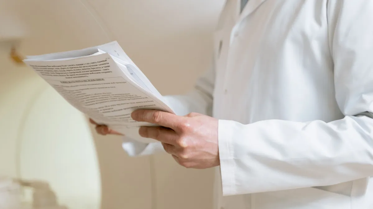 Doctor in a white coat examining medical papers in a healthcare setting.