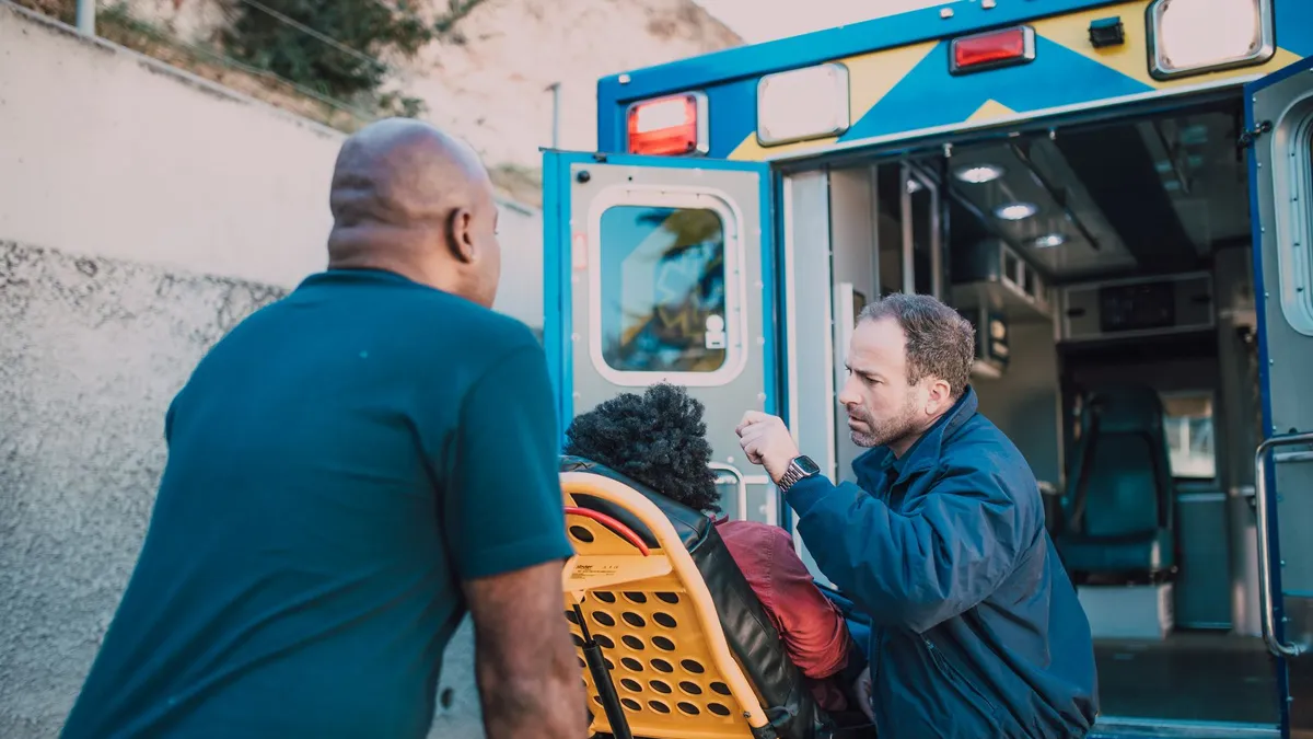 First responders assisting a patient into an ambulance for medical aid.