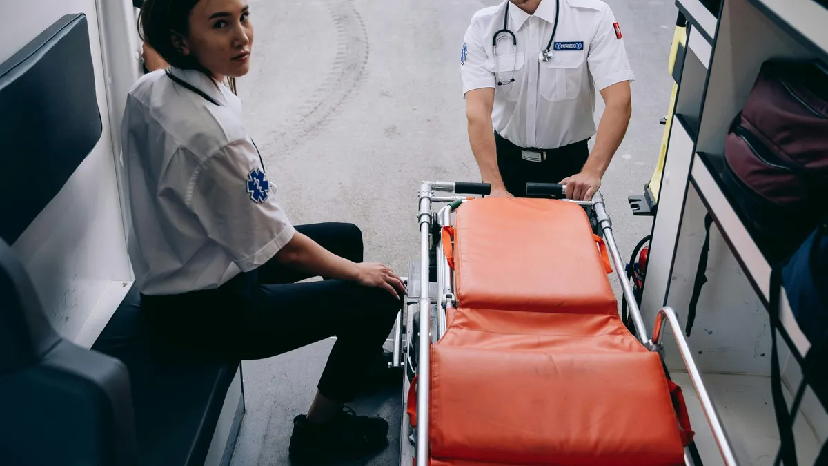 Two paramedics prepare a stretcher inside an ambulance, ready for an emergency response.