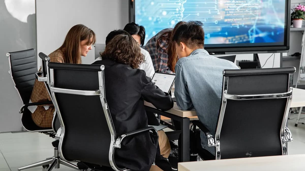 A diverse team collaborating in a modern office environment with a digital display.