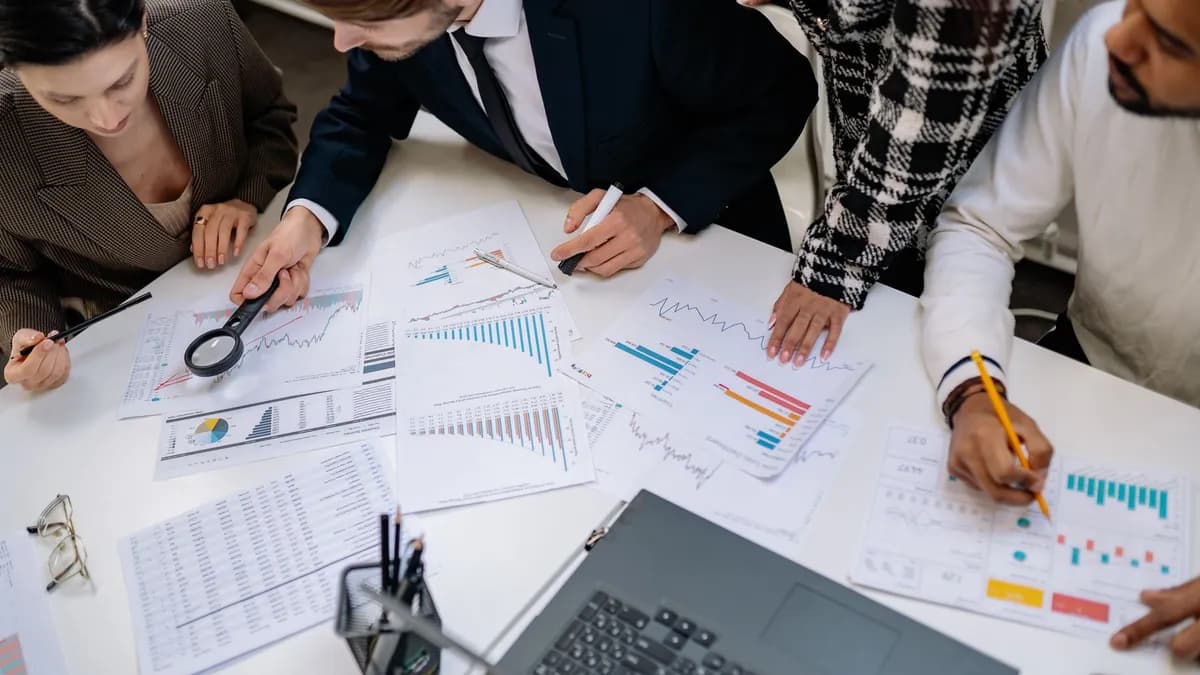 A group of professionals reviewing financial charts in an office meeting setting.