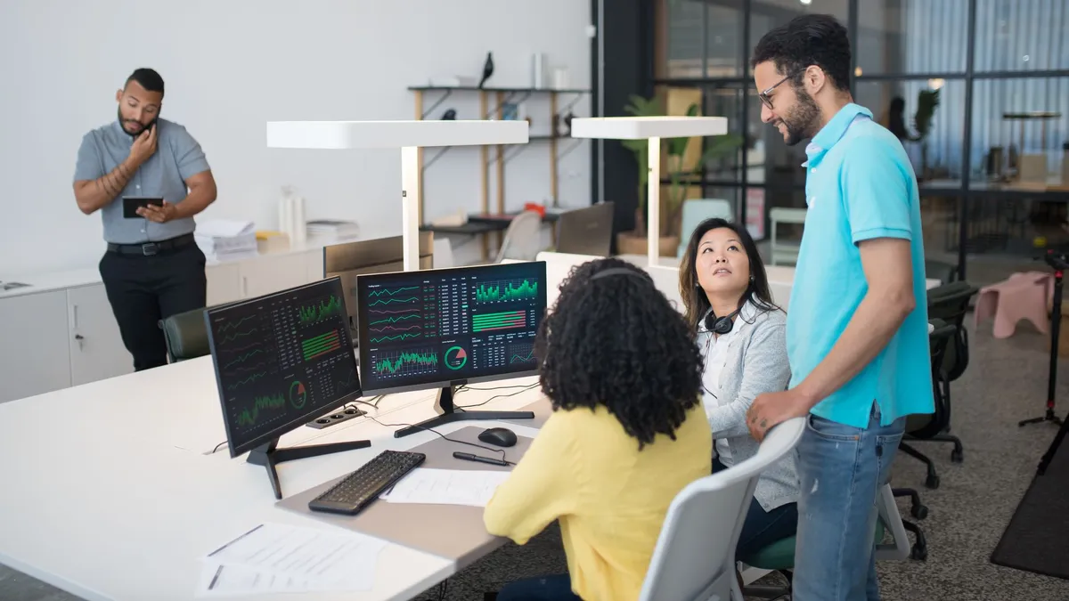 Office employees collaborate on financial data at modern workspace, engaging in teamwork and communication.