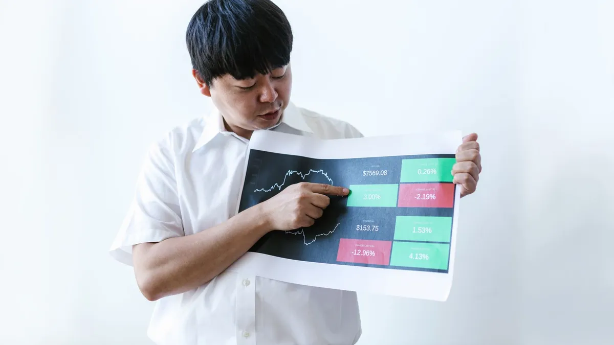 Asian businessman in white shirt presenting cryptocurrency market data on chart.